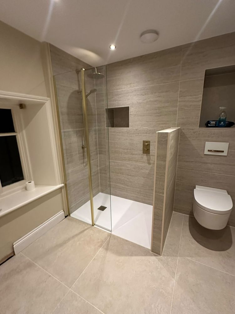 Walk-in shower with brushed brass fittings, tiled niche and wall-hung toilet
