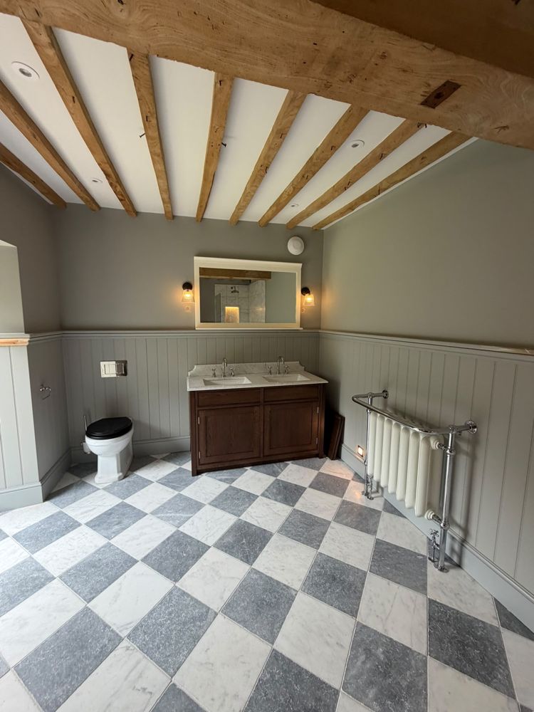 Traditional bathroom with oak beams, double vanity unit, chequered marble floor and a traditional towel radiator