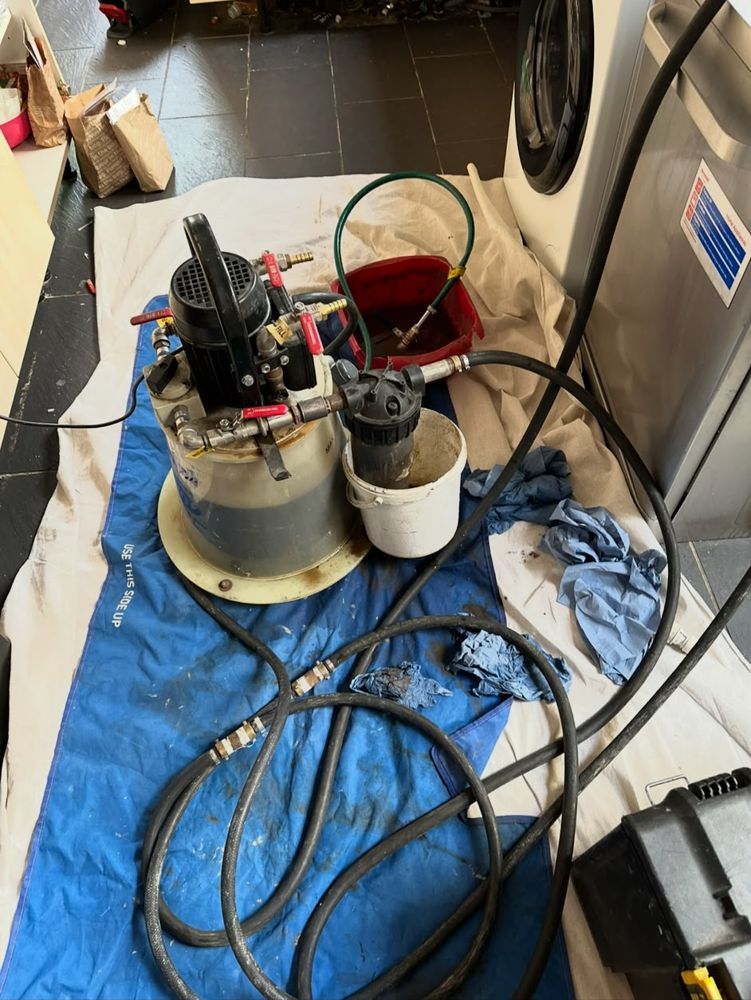 Power flushing pump set up on dust sheets in a kitchen