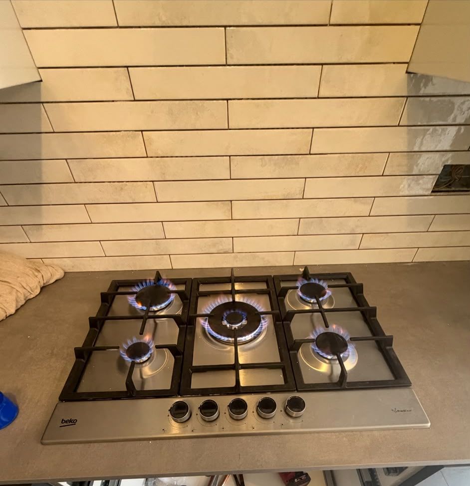 Five-burner gas hob fitted and lit, with all burners on test