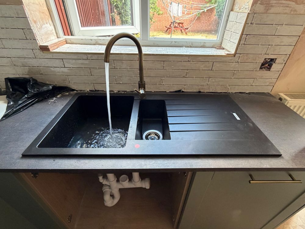 Black 1.5-bowl kitchen sink with a brass tap during a kitchen refit