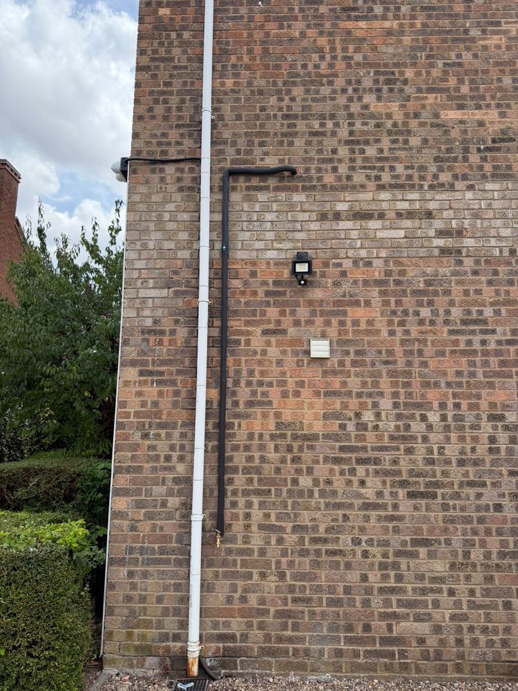 Outside tap with an insulated supply pipe run down a brick wall
